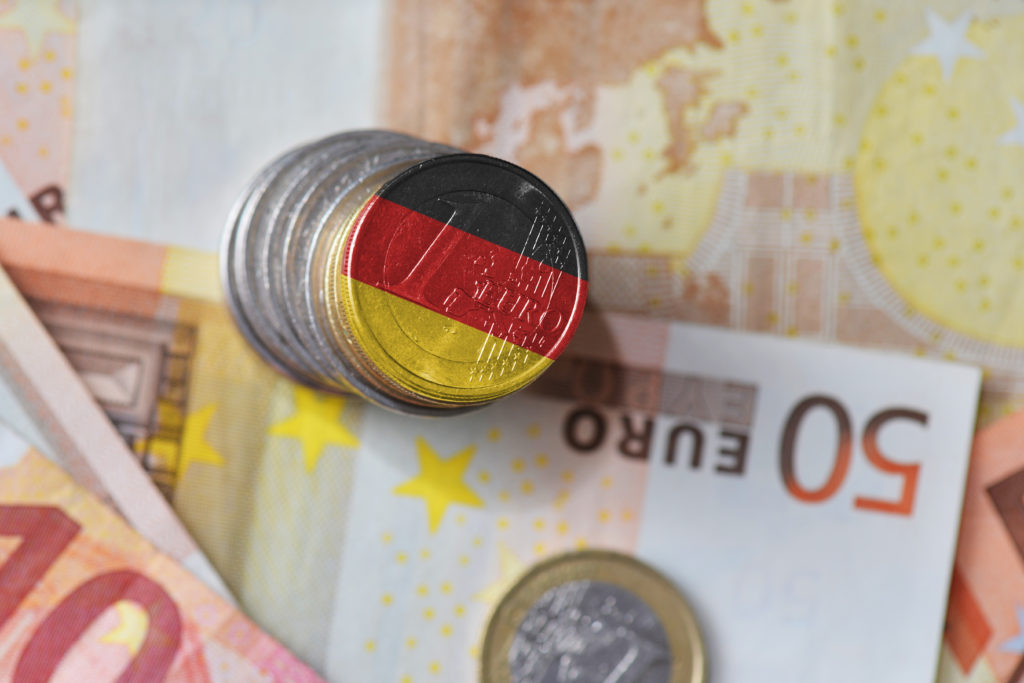 Stack of euro coins and bills with the German flag painted on a coin
